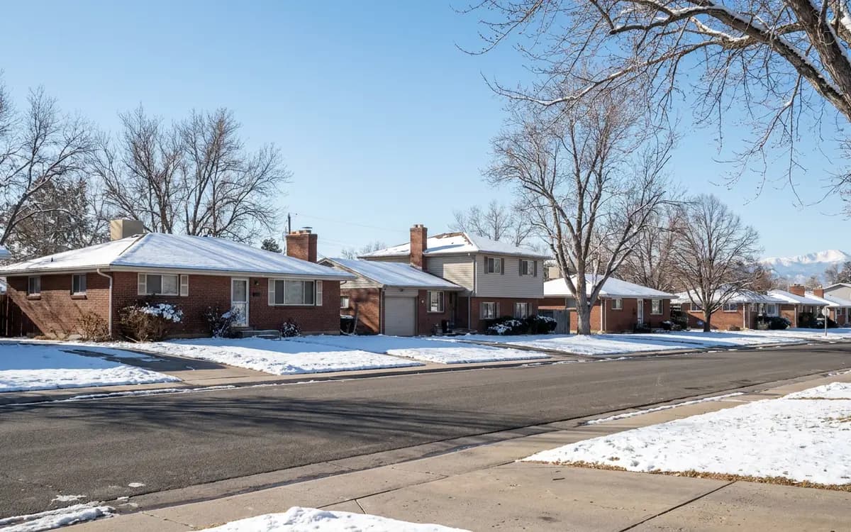 Row of older ranch and two-story houses along a quiet suburban street on a clear winter day