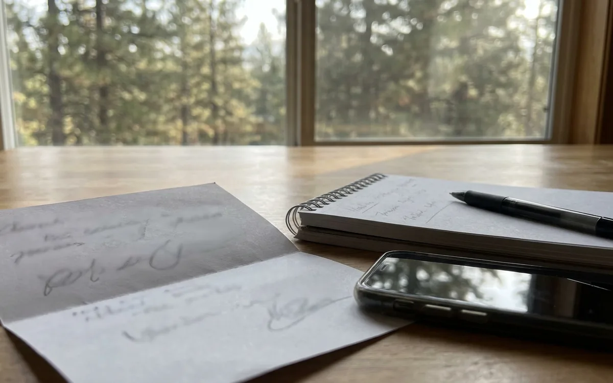 Kitchen table with a utility bill, handwritten notepad, pen and smartphone in morning light